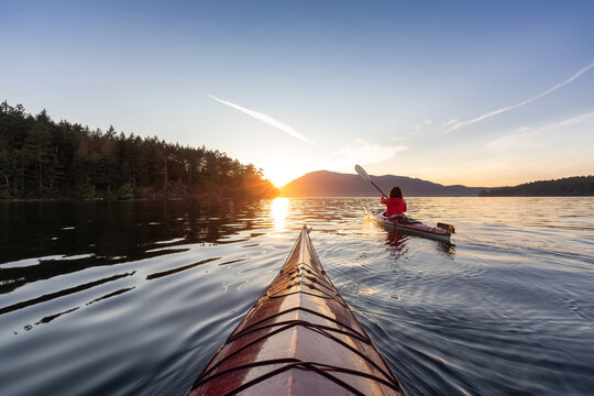 冒险的女人在海上皮艇划桨在太平洋。阳光灿烂的夏日日落。摄于维克多附近