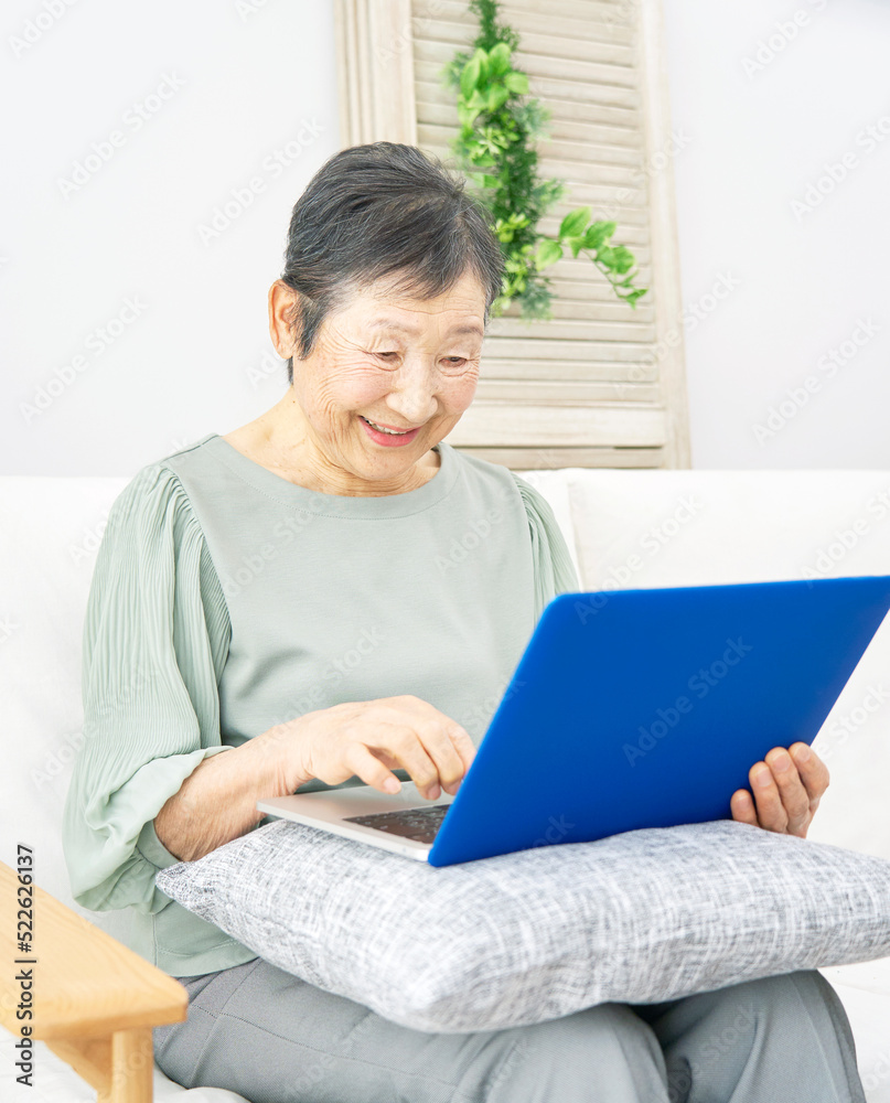 自宅でノートパソコンを使うシニア女性