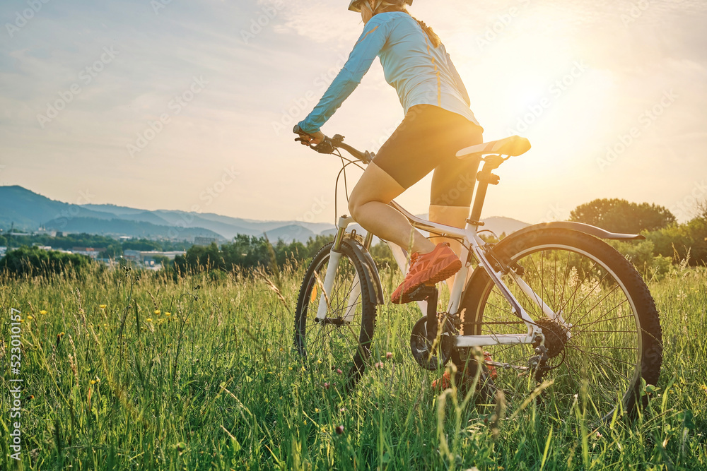 戴着头盔骑自行车的骑自行车的女子在阳光明媚的一天在森林中的一座山上进行户外运动。Si