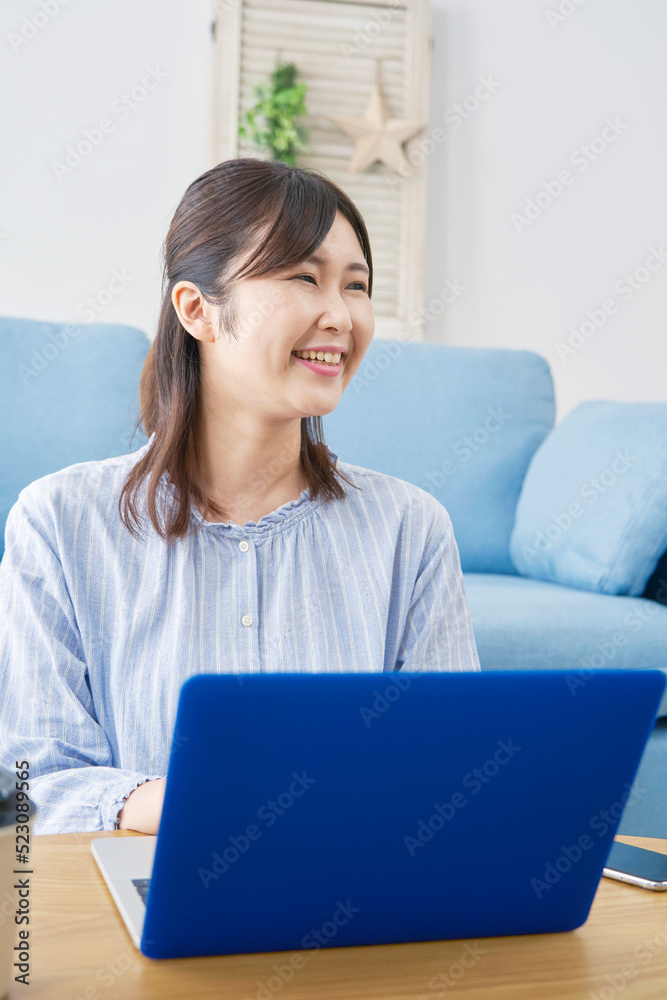 自宅でノートパソコンを使う女性のカメラ目線ポートレート