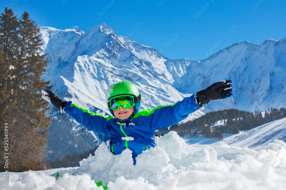 男孩在雪堆里举起双手站着玩