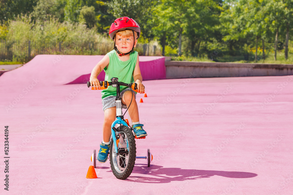 金发男孩骑小自行车，学习轮绕着圆锥体