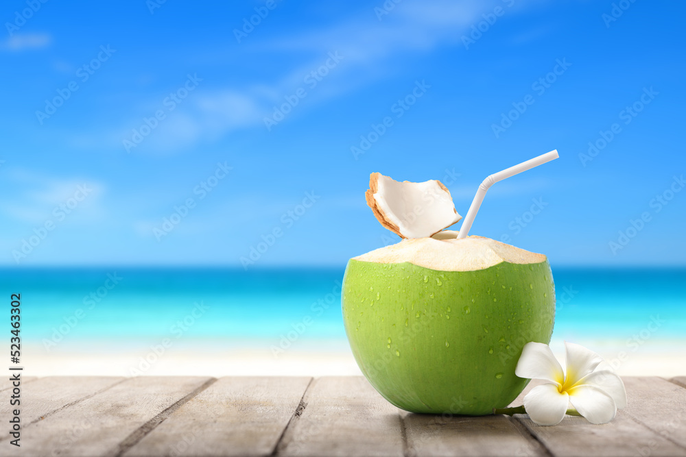 清凉的椰子汁放在沙滩背景的木桌上。