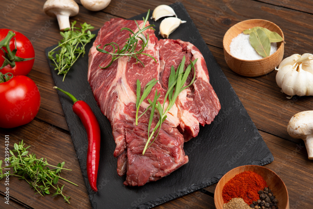 木制桌面上的生牛排。健康食品概念。牛肉块和烹饪烧烤酱的香料