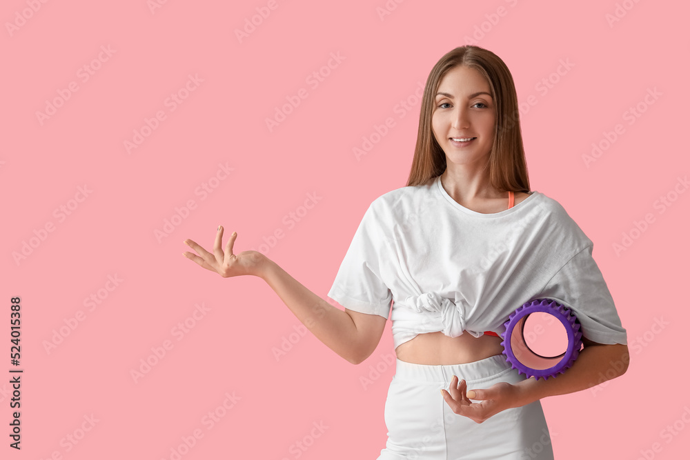 带着泡沫滚筒的年轻女子在粉色背景上展示了一些东西