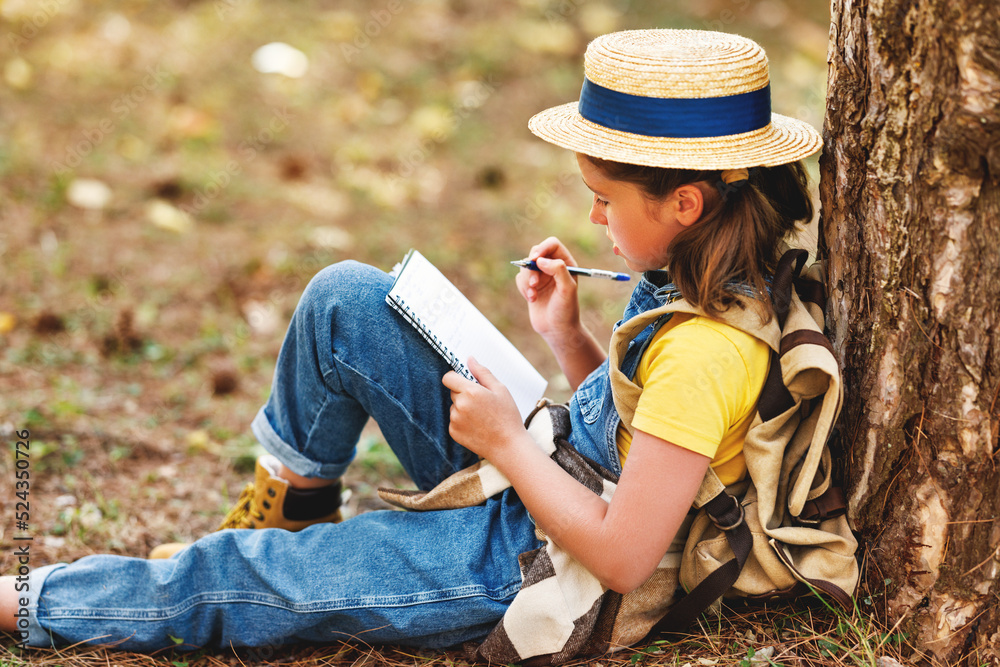 小女孩在森林里散步时在笔记本上做笔记