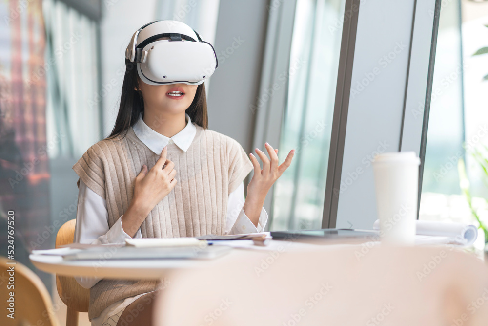 聪明迷人的亚洲女企业主戴着虚拟现实眼镜，享受休闲的元宇宙