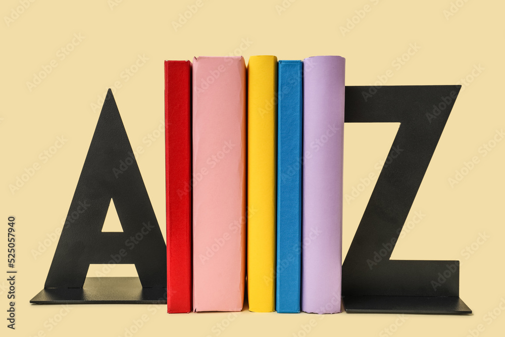 Books with stands in shape of letters on beige background