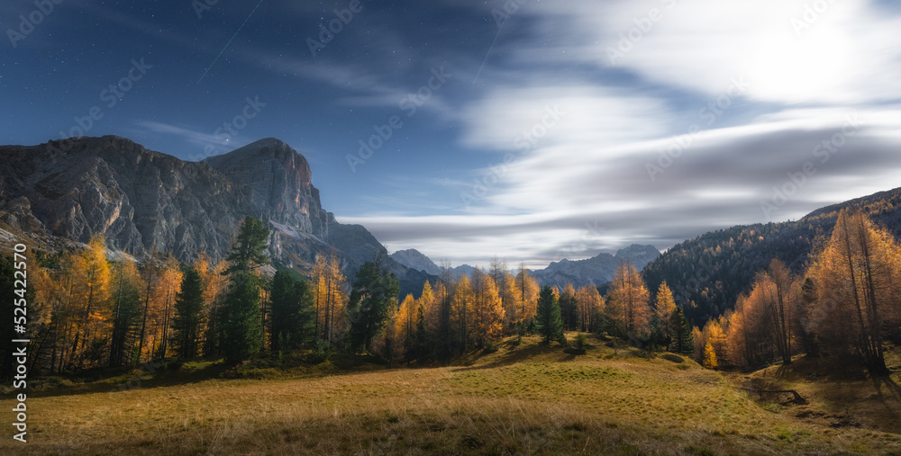 Full moon over the mountains in Dolomites alps at starry night in autumn. Italian alps. Colorful lan