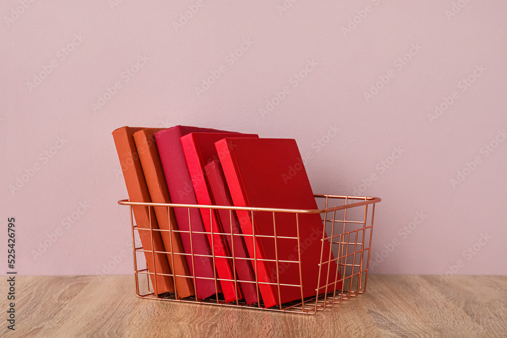 粉红色墙壁附近桌子上有书的金属篮子