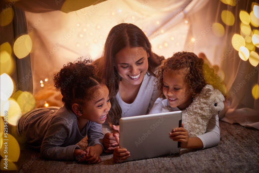 母亲和孩子们在平板电脑或数字儿童应用程序上直播电影，晚上在帐篷里露营