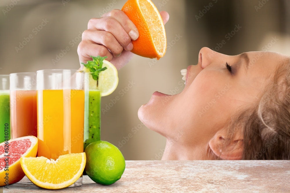 Confident young woman in sports clothing drinking orange while standing at the kitchen