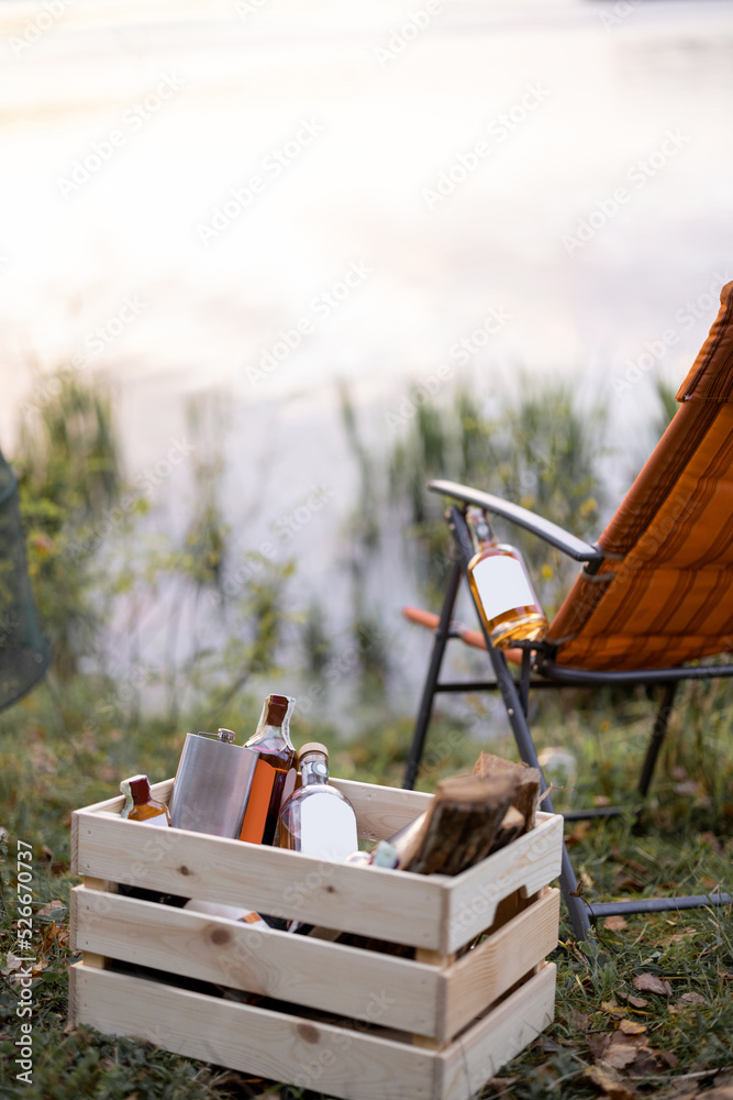 野餐或钓鱼时，木箱和折叠椅上放有烈性酒精的瓶子。空白瓶子