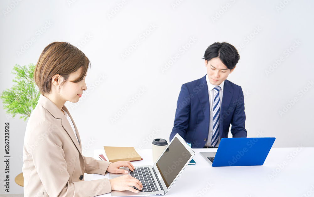 オフィスでノートパソコンを使うビジネスウーマンとビジネスマン