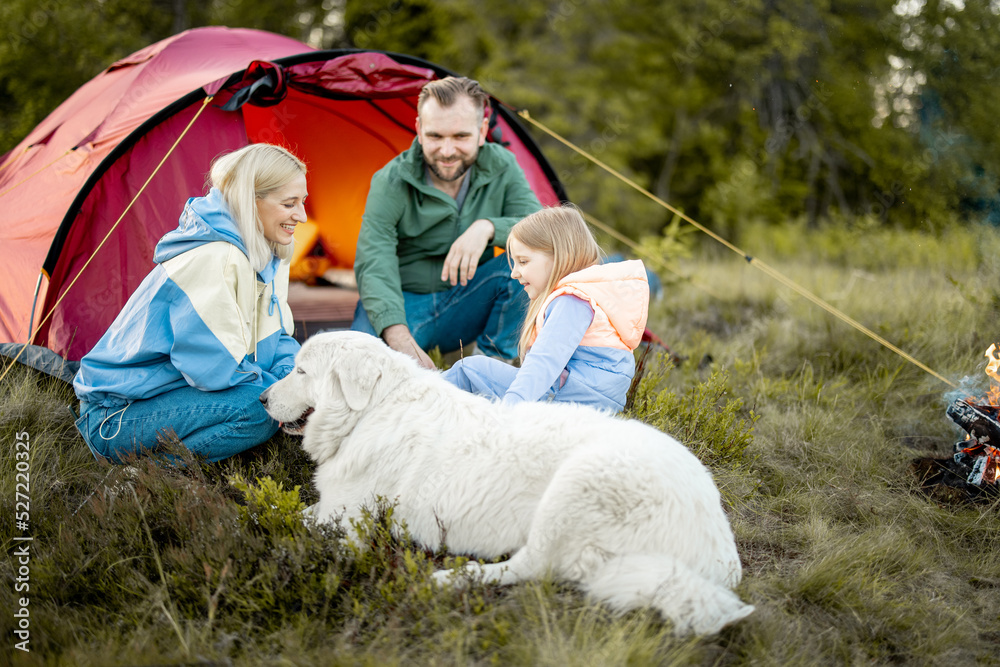 一对年轻夫妇带着一个小女孩在露营地玩得很开心，带着帐篷在大自然中旅行。家人一起度过难关