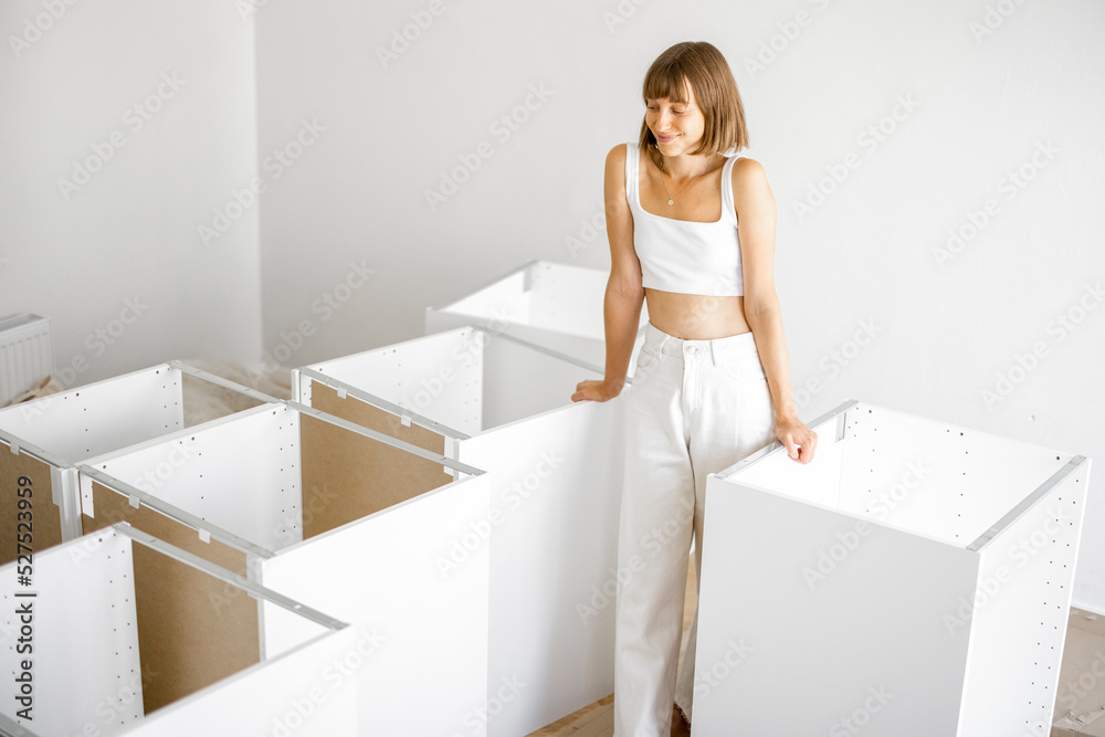 一位年轻快乐的家庭主妇的画像，拿着公寓里的新家具。一位穿着白色衣服的女人