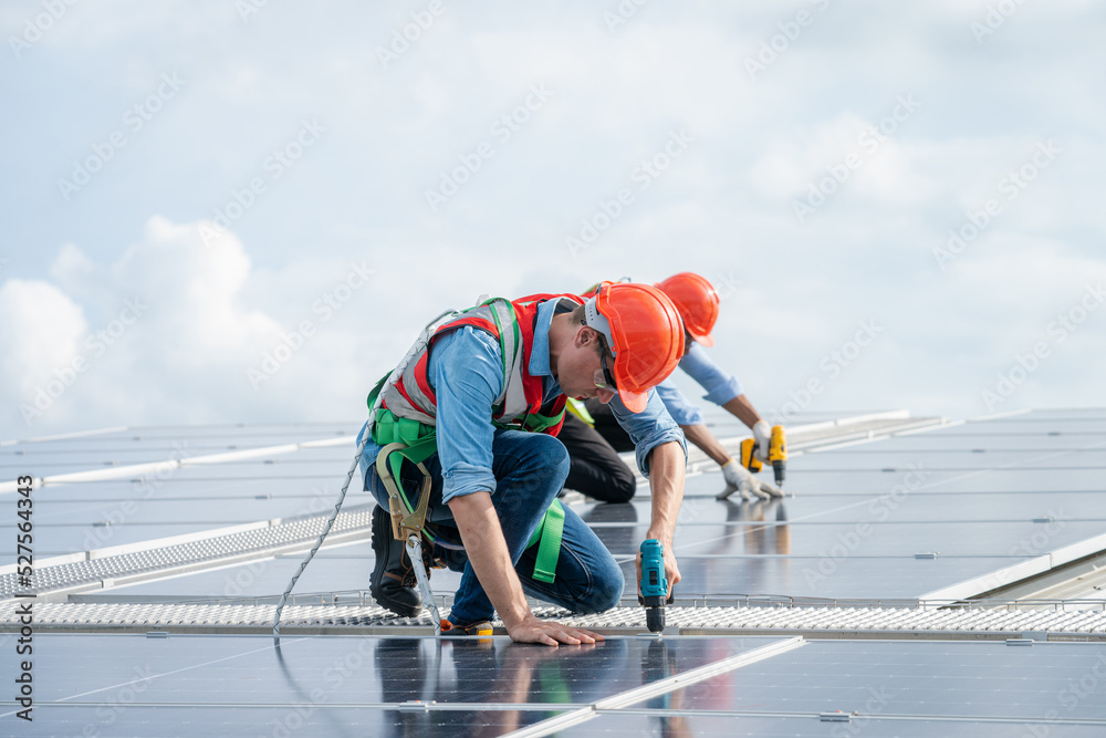 工程师使用钻机在住宅区的屋顶结构上安装太阳能电池板，绿色能源公司