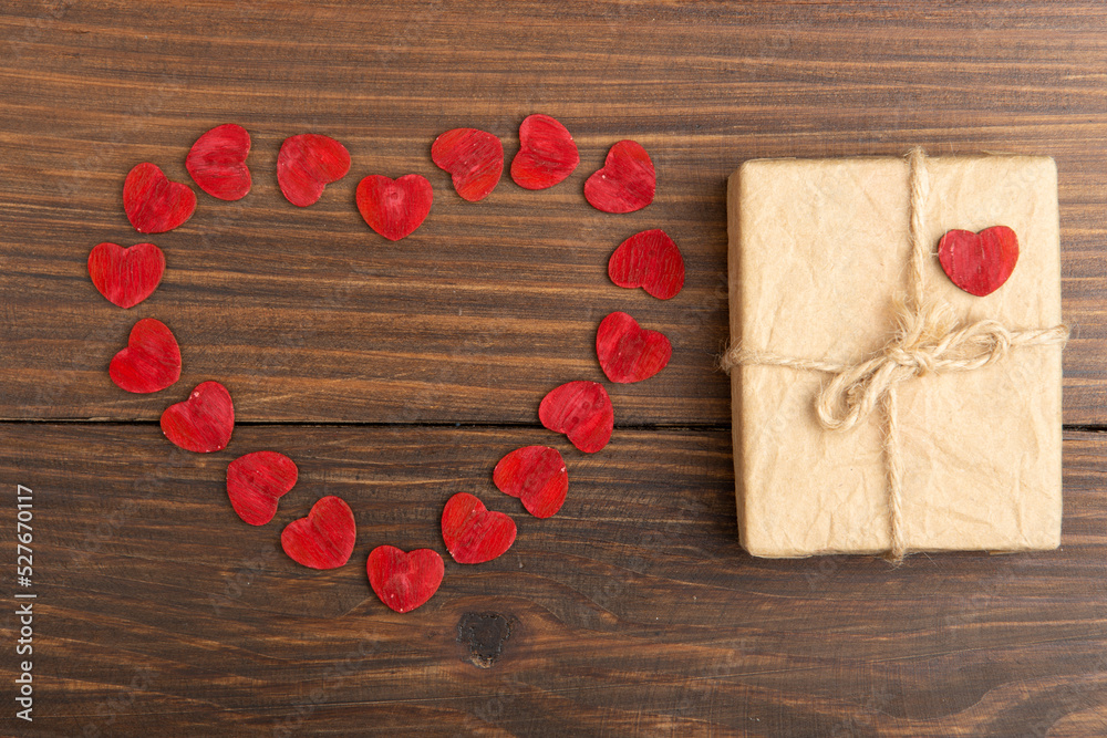 情人节问候概念。木制十字架上的红色木制小爱心和礼品盒