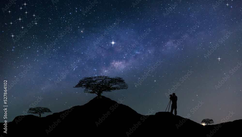 旅行者男人剪影站在山顶。全景蓝色夜空乳白色，星星在黑暗的背面。