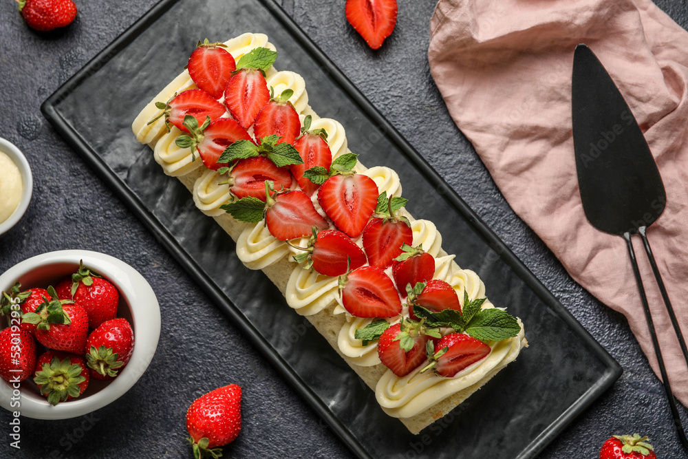 深色背景上有美味的草莓卷蛋糕和浆果的木板