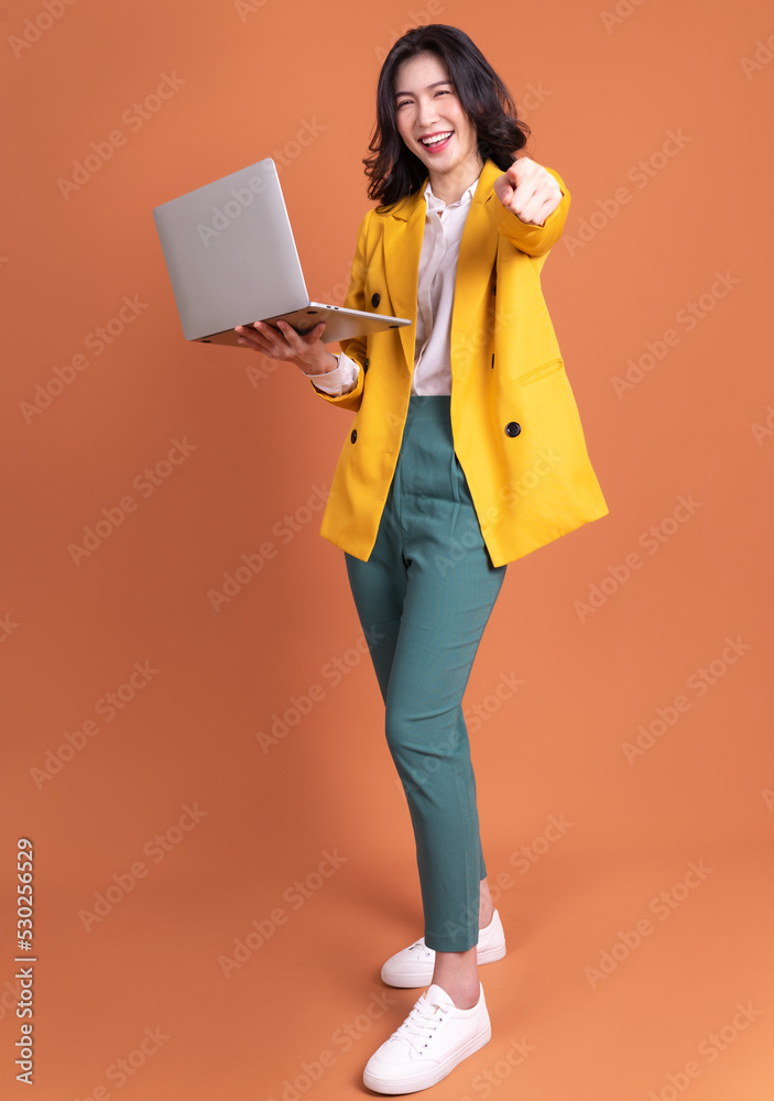 年轻亚洲女性使用笔记本电脑作为背景的全长照片