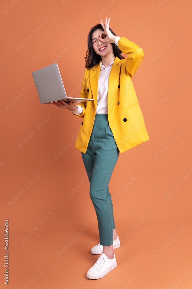 年轻亚洲女性使用笔记本电脑作为背景的全长照片