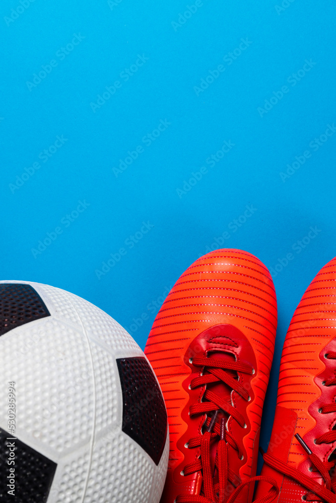 蓝色背景下的足球和红色鞋子的构图，带有复制空间