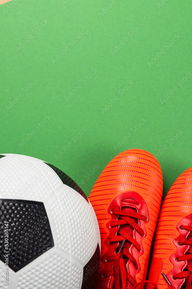 橙色足球靴和绿色背景足球的图像，带有复制空间
