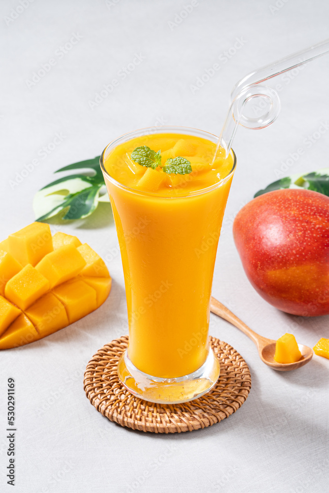 Fresh beautiful delicious mango juice smoothie in glass cup on gray table background.