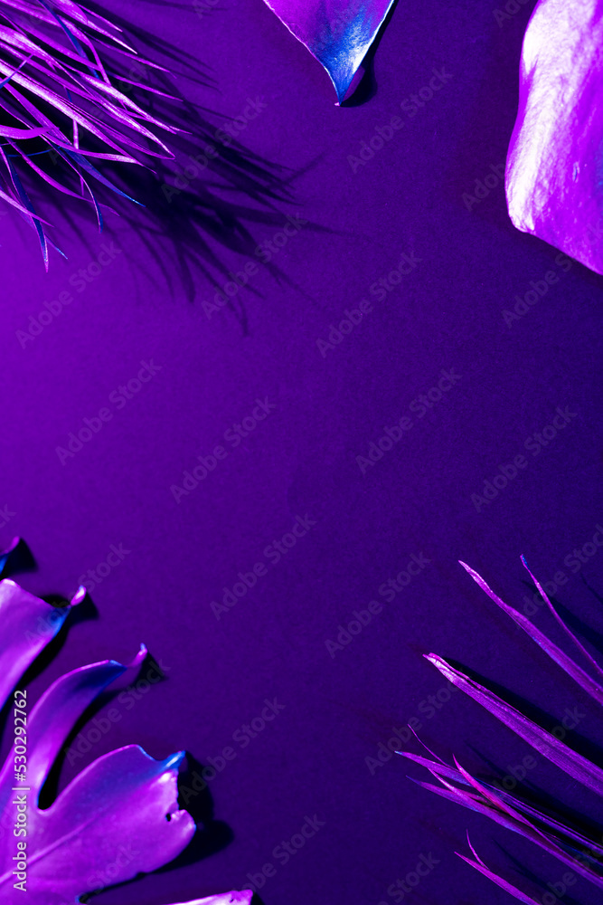 Image of vibrant neon lit purple leaves over purple background with copy space