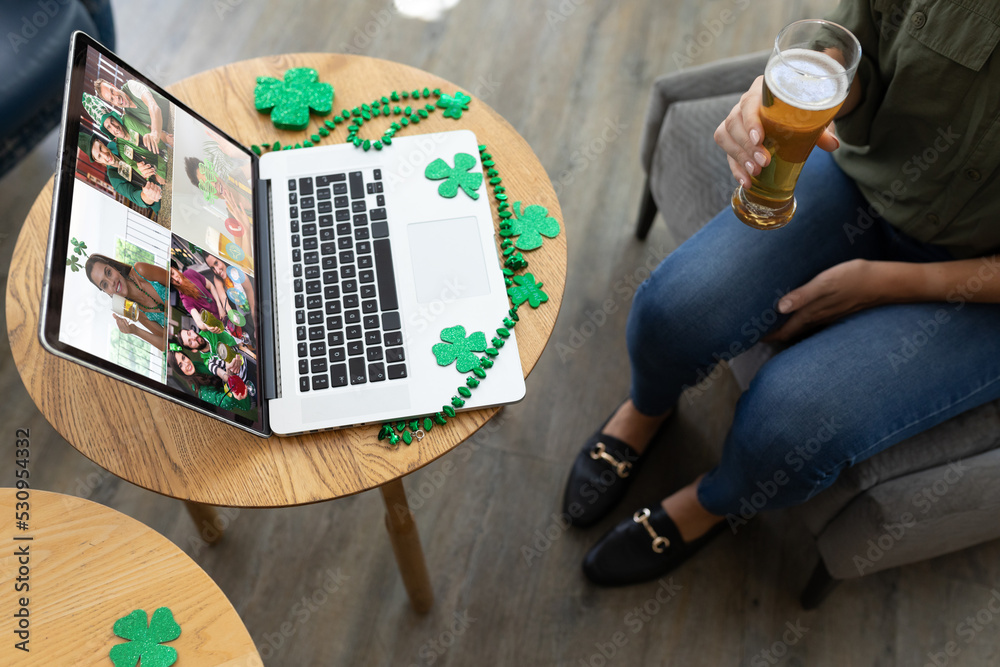 Mid section of woman holding beer while having a video conference on laptop at a bar