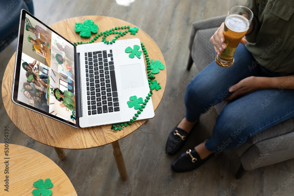 酒吧里拿着啤酒在笔记本电脑上开视频会议的女人的中段