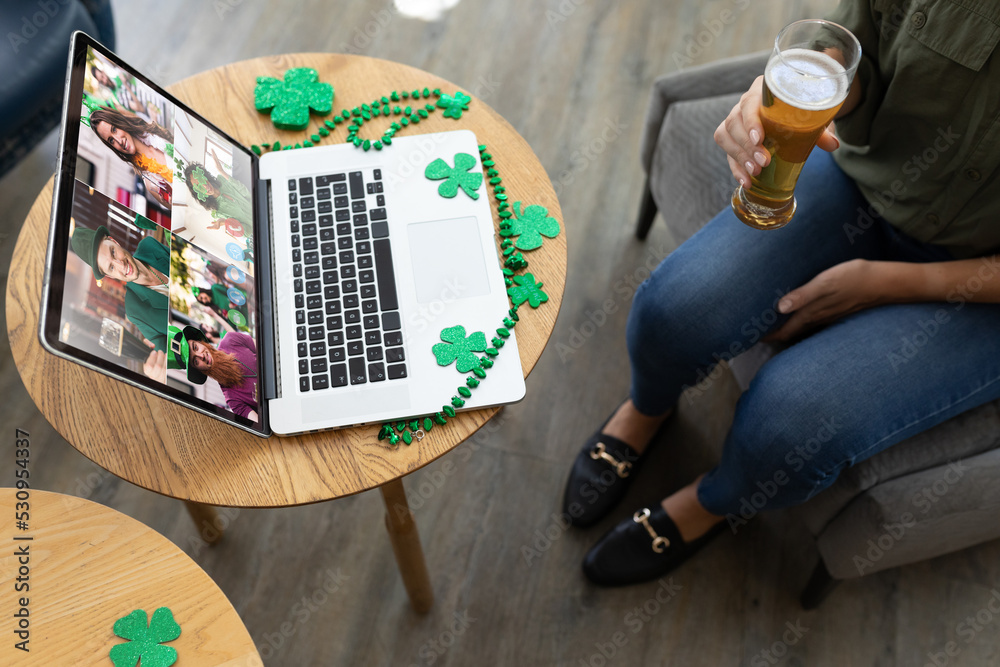 在酒吧用笔记本电脑进行视频会议时，一名女子拿着啤酒的中段