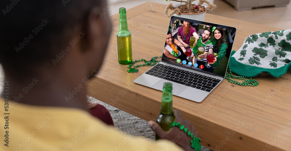 一名非裔美国人拿着啤酒在家里用笔记本电脑进行视频通话