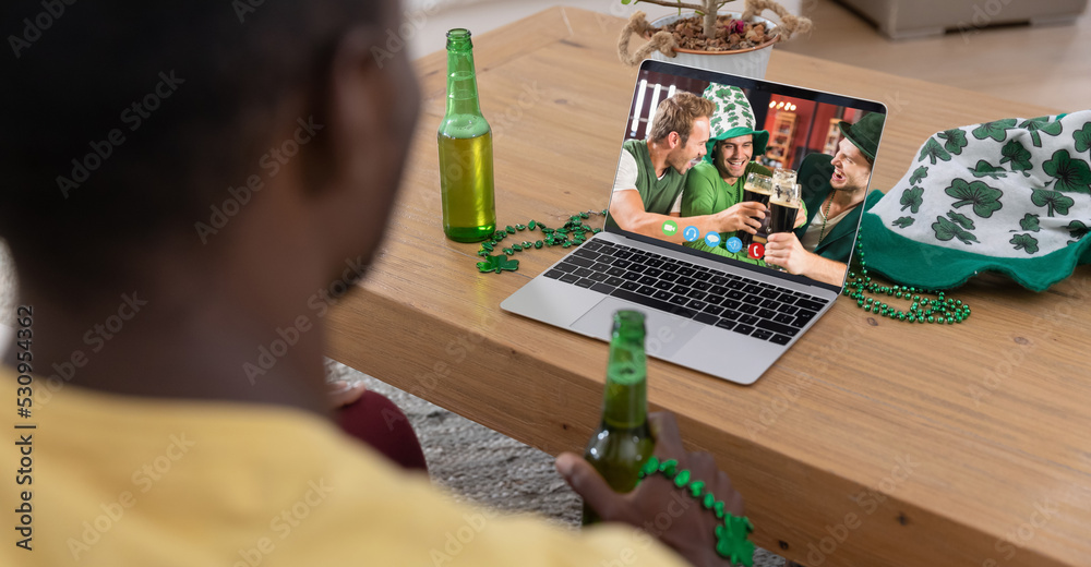 一名非裔美国人拿着啤酒在家里用笔记本电脑进行视频通话