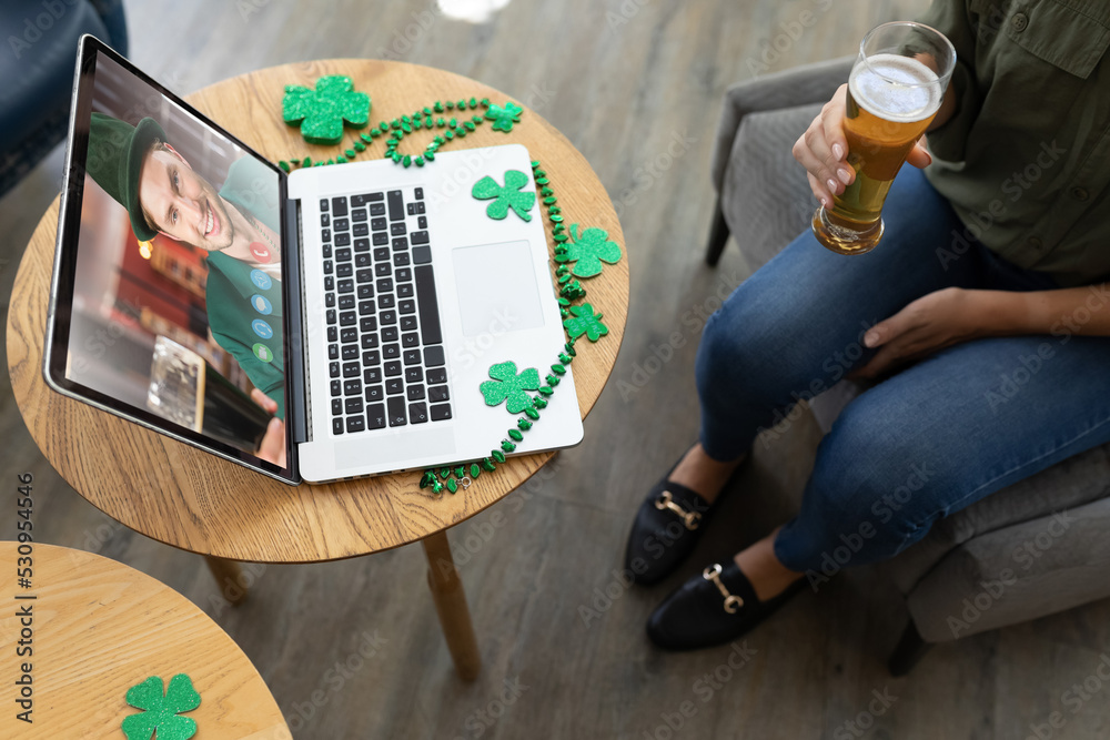 在酒吧用笔记本电脑召开视频会议时，女人拿着啤酒杯的中段