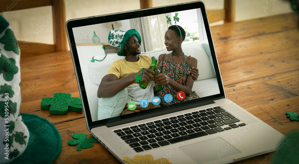 一对非洲裔美国夫妇在木制桌子上的笔记本电脑上通过视频通话敬酒的网络摄像头视图