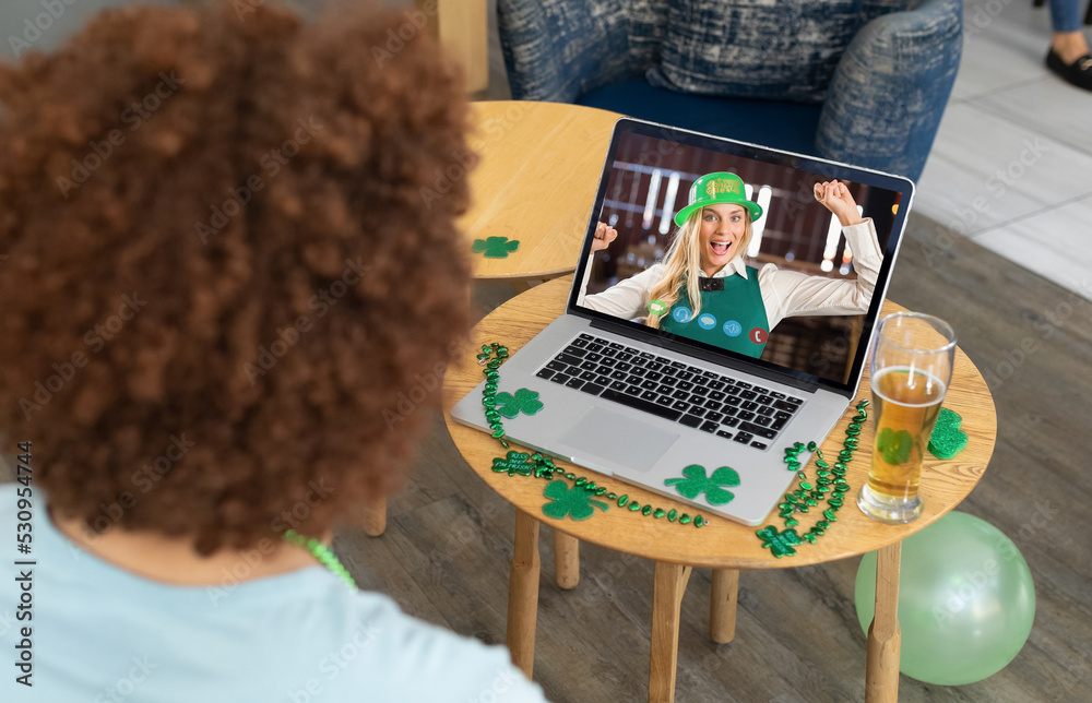 酒吧里的混血男子在笔记本电脑屏幕上与穿着戏服的女子进行圣帕特里克节视频通话