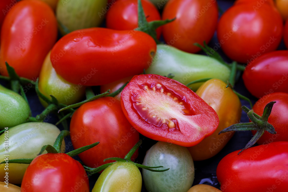食物背景，俯视特写，切成五颜六色的新鲜樱桃番茄的一半，黑色上有绿色和红色
