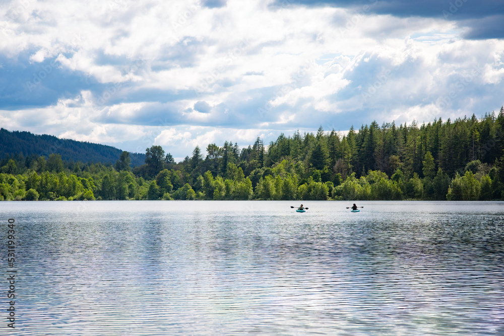 两名妇女在华盛顿州太平洋西北部一个原始的山湖上划皮划艇。风景如画