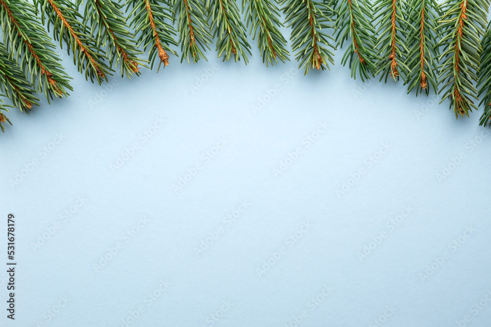 创意圣诞假期背景，蓝色硬纸板背景上有冷杉枝。平躺，