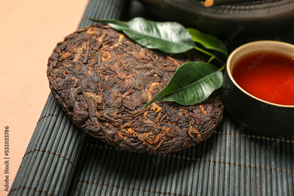 米色背景上的竹垫和干压制的普洱茶，特写
