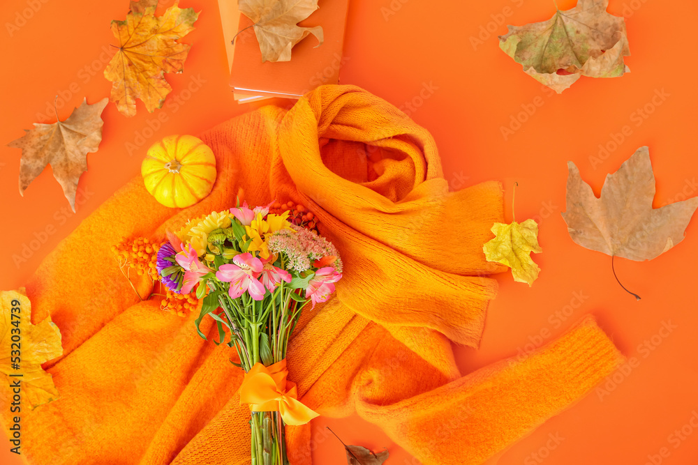 温暖的女性毛衣、围巾、花束和橙色背景的秋季装饰