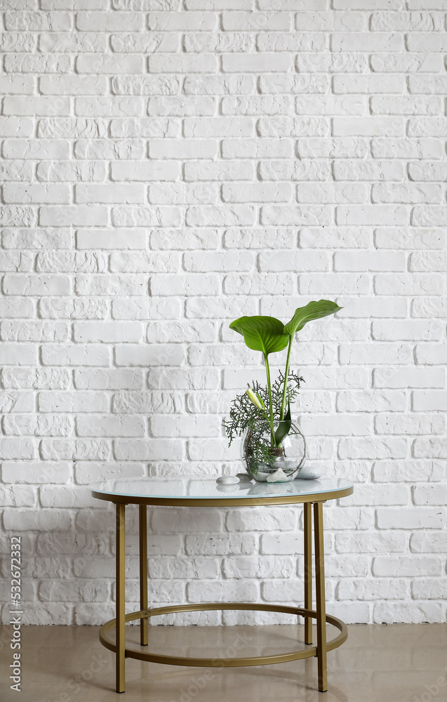 白色砖墙附近的桌子上放着漂亮的插花和水疗石的碗