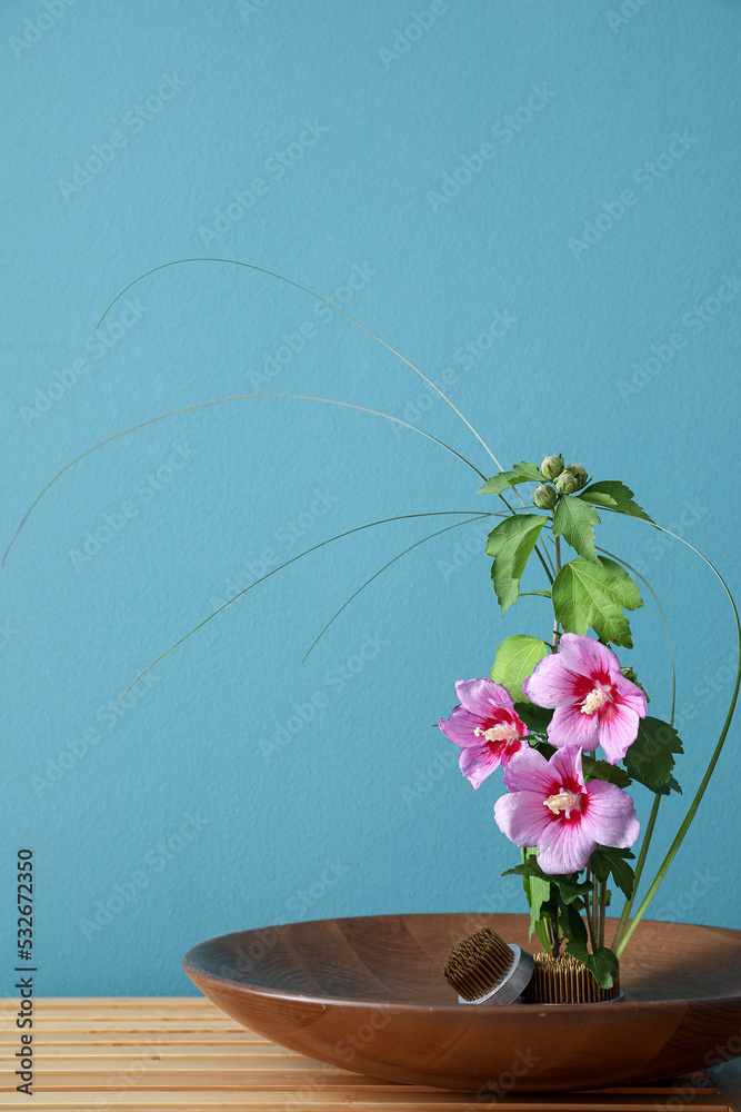 蓝墙附近的木桌上摆放着漂亮的插花和kenzans碗