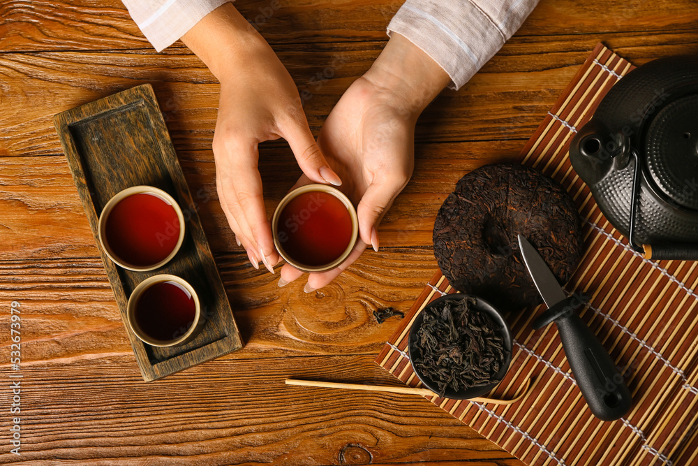 女性手拿一杯木底芳香的普洱茶