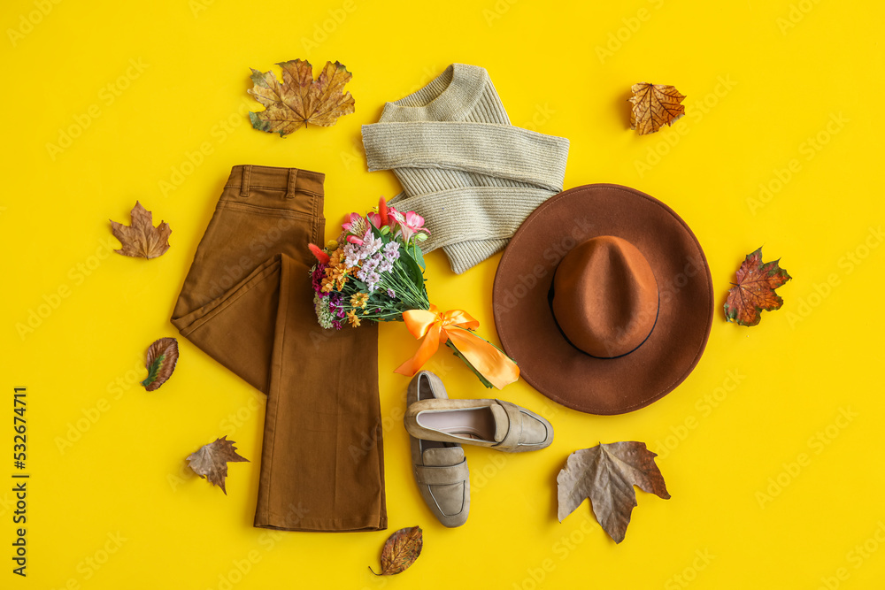 黄色背景下美丽的花朵与时尚的衣服、鞋子、帽子和秋叶的花束