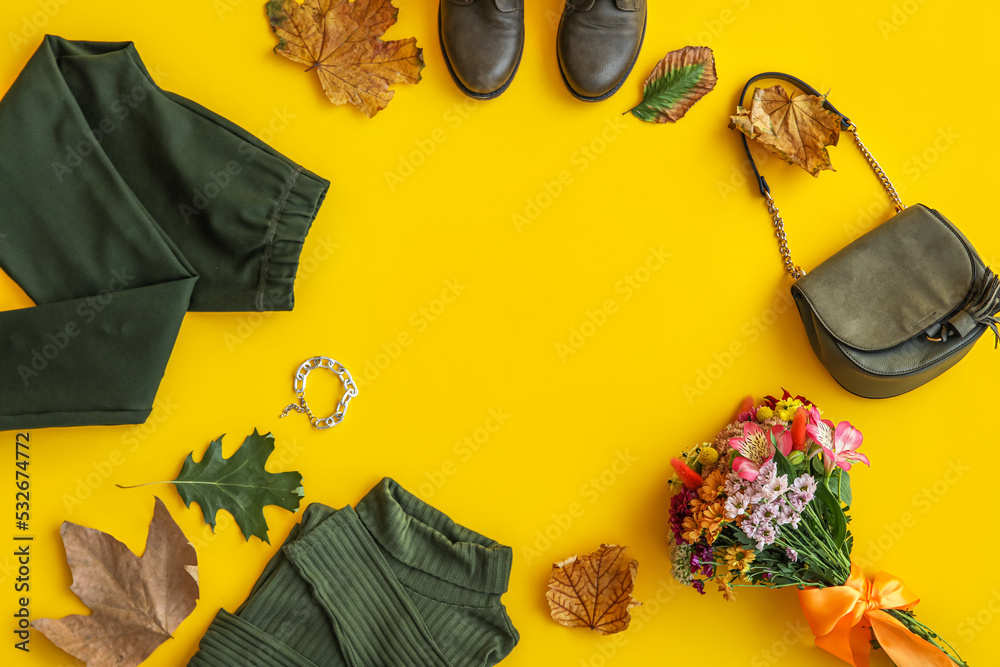 由黄色背景的时尚衣服、鞋子、配饰、花朵和秋叶制成的框架