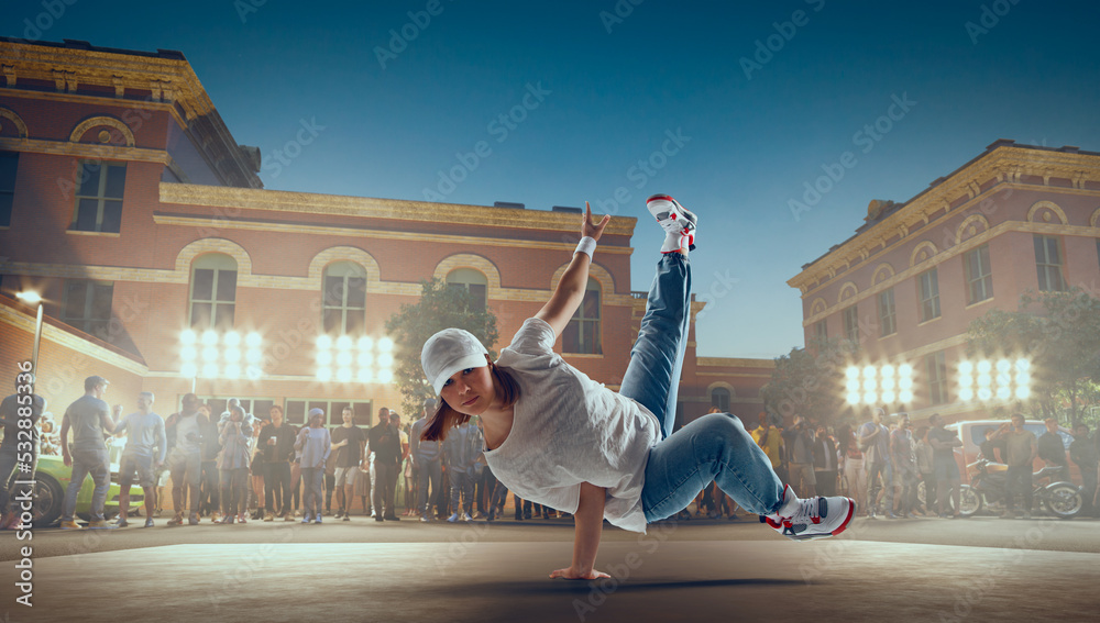 街头舞者女孩在晚上的街道上跳霹雳舞