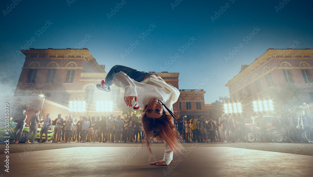 街头舞者女孩在晚上的街道上跳霹雳舞